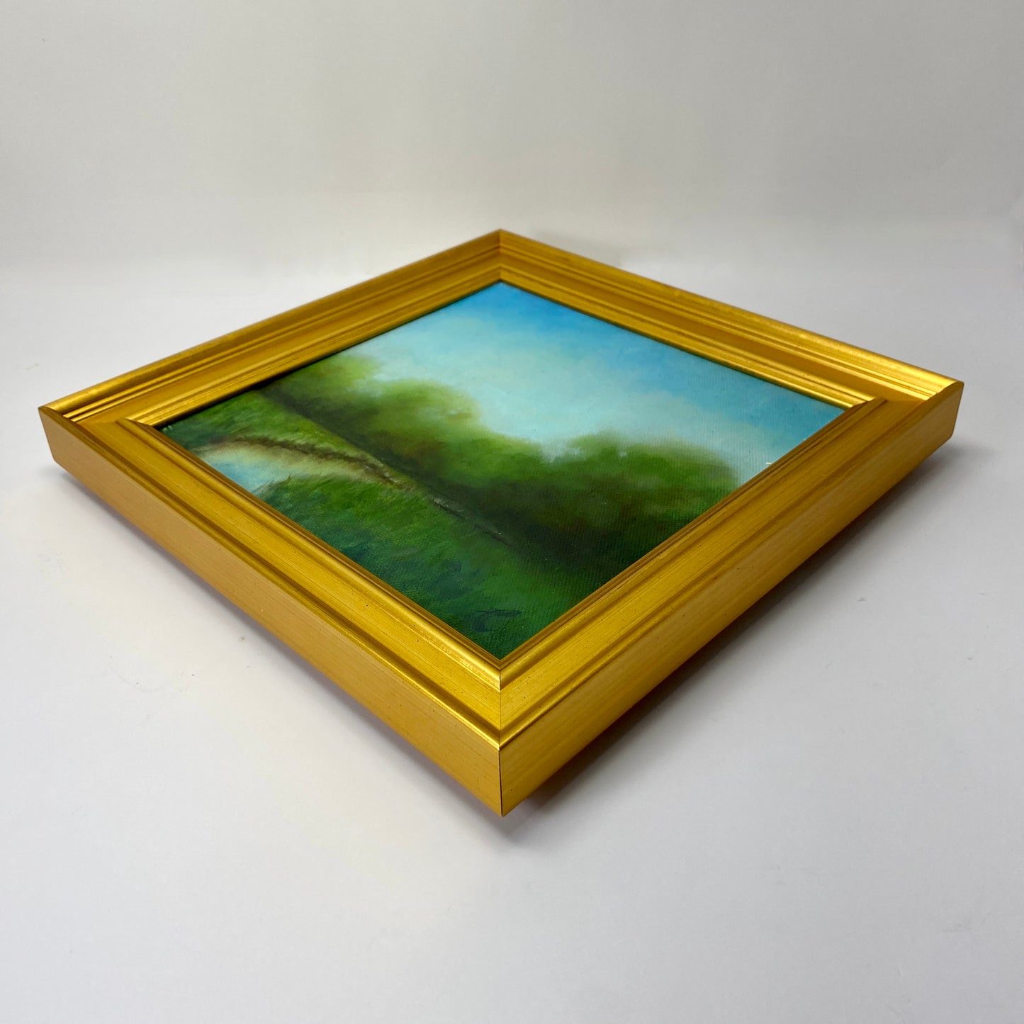 Original oil landscape painting with a gold frame on a white background