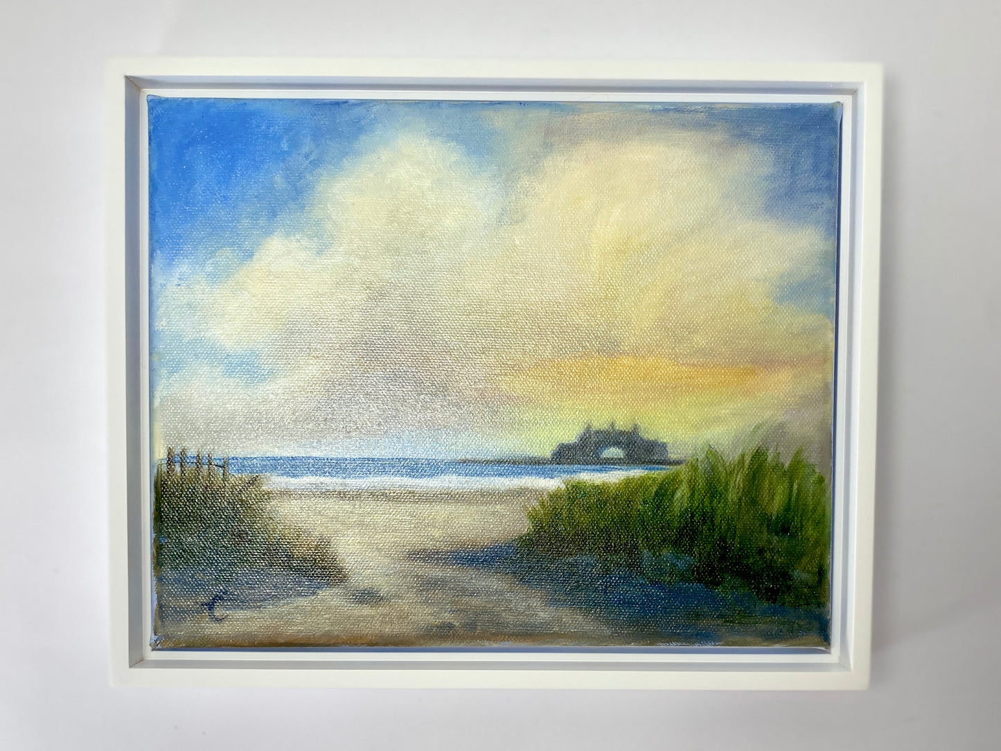 Framed painting of a Narragansett beach and Towers scene with grass and water.
