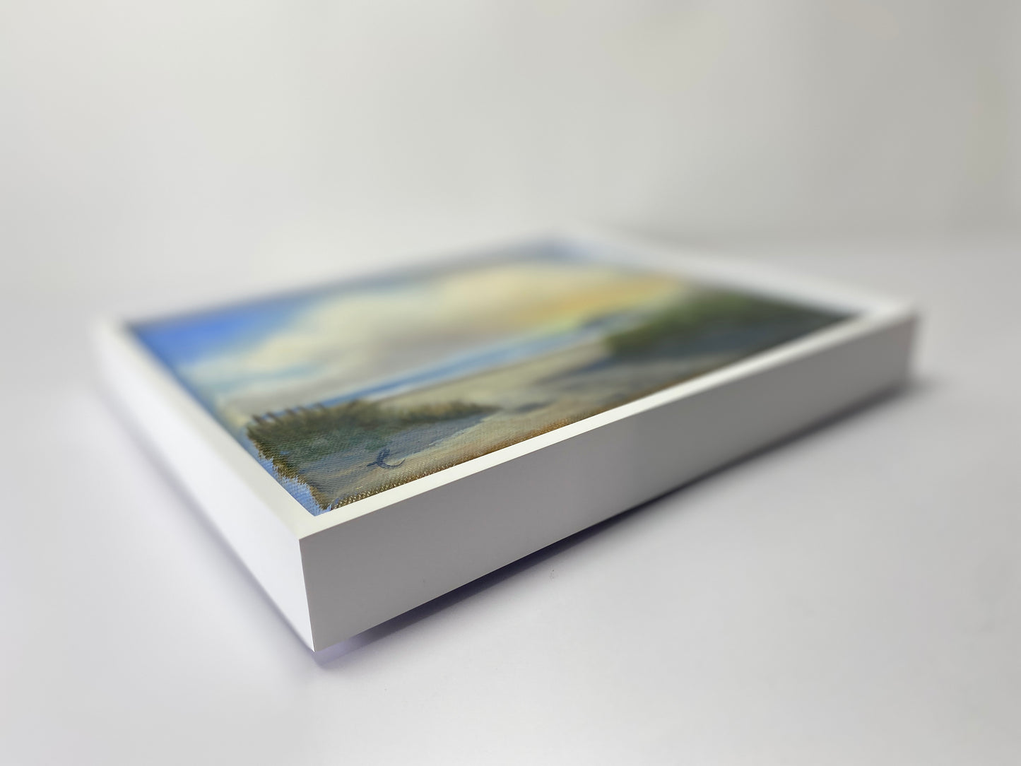 Framed artwork of a landscape on a white surface