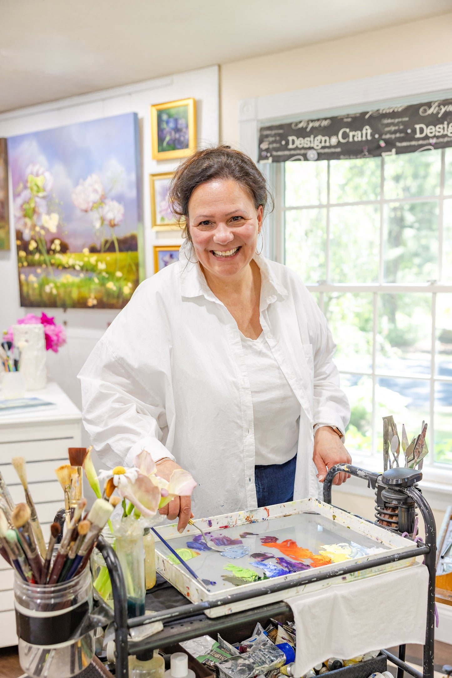 Artist Carla Thomson mixing vibrant oil paints on her palette, surrounded by light and color in her Rhode Island studio.