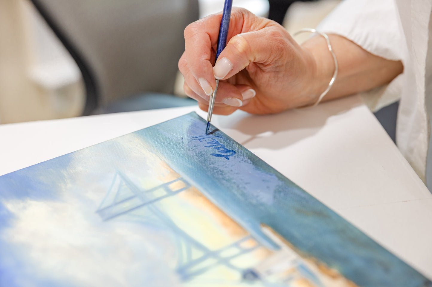 Close up of artist Carla Thomson signing an original oil painting