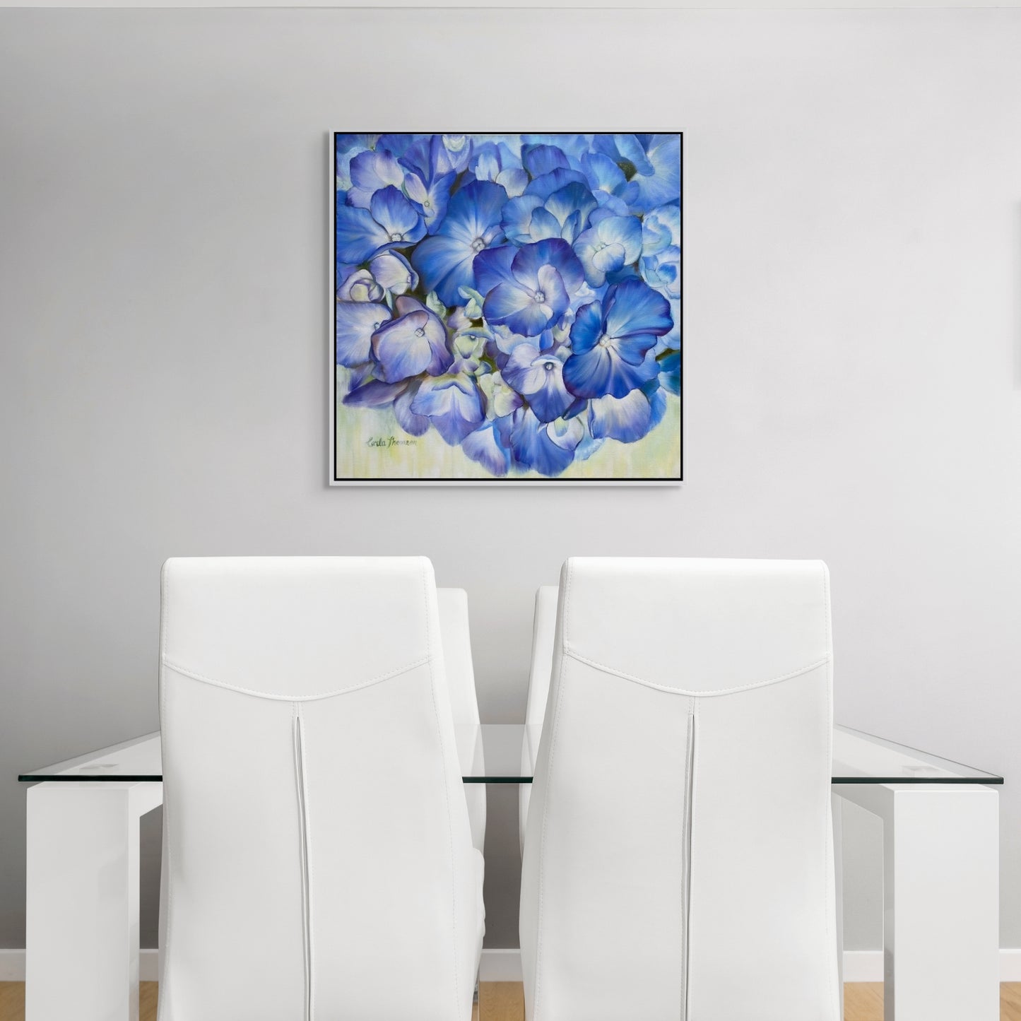 Dining room featuring Echoes of Blue original oil painting on white wall over a glass table with white chairs.