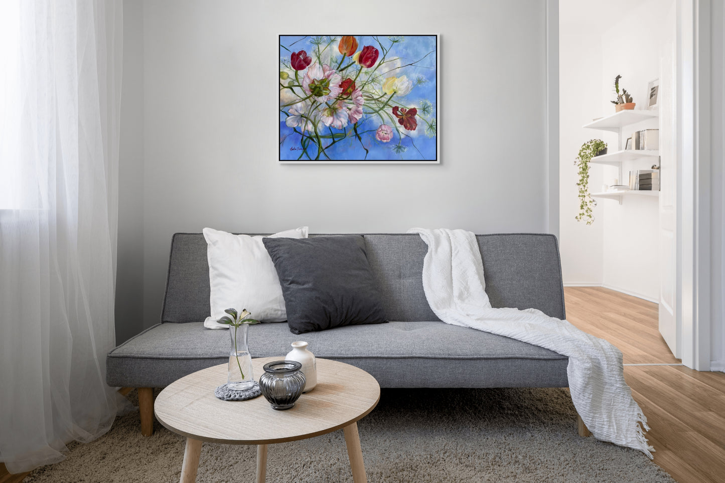 Modern living room with a gray sofa, round wooden coffee table, and Wishful Thinking a colorful original floral oil painting on the wall.