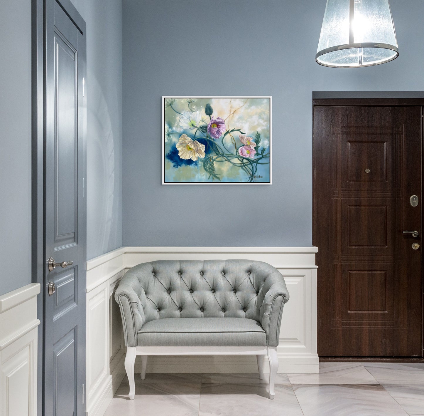 Foyer with gray tufted sofa, original floral oil painting Tangled Reverie on wall, and wooden door.