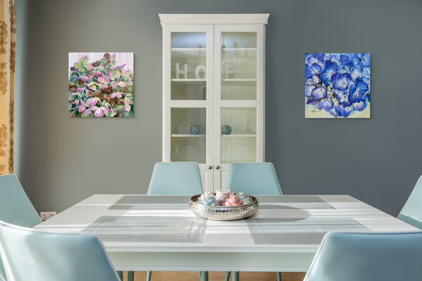Dining room with a table, chairs, and set of original oil paintings Whispers in Time and Echoes in Blue floral artwork on the walls.