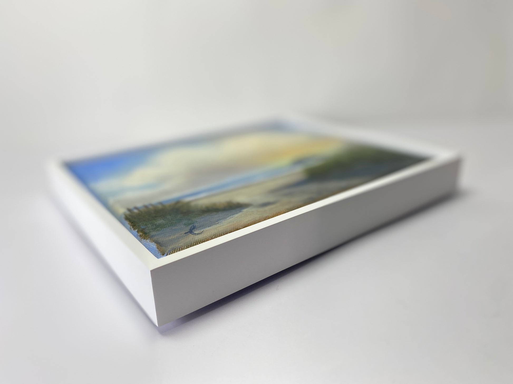 Framed artwork of a landscape on a white surface