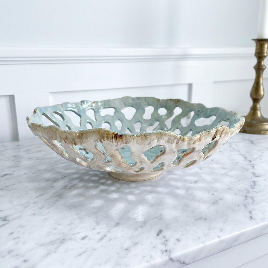 Openwork: Coastal — Tidepool ceramic bowl on marble surface with brass candlestick, showing celadon interior and cream exterior glaze