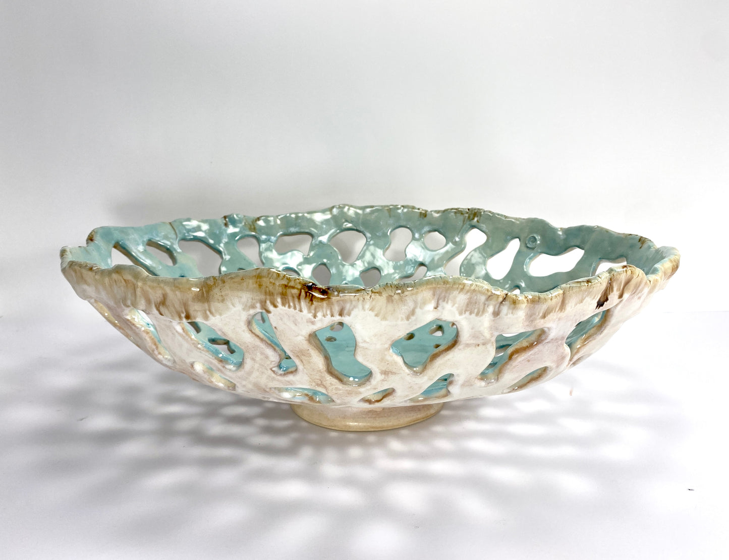 Openwork: Coastal — Tidepool, three-quarter view showing cream and earth exterior glaze with celadon interior