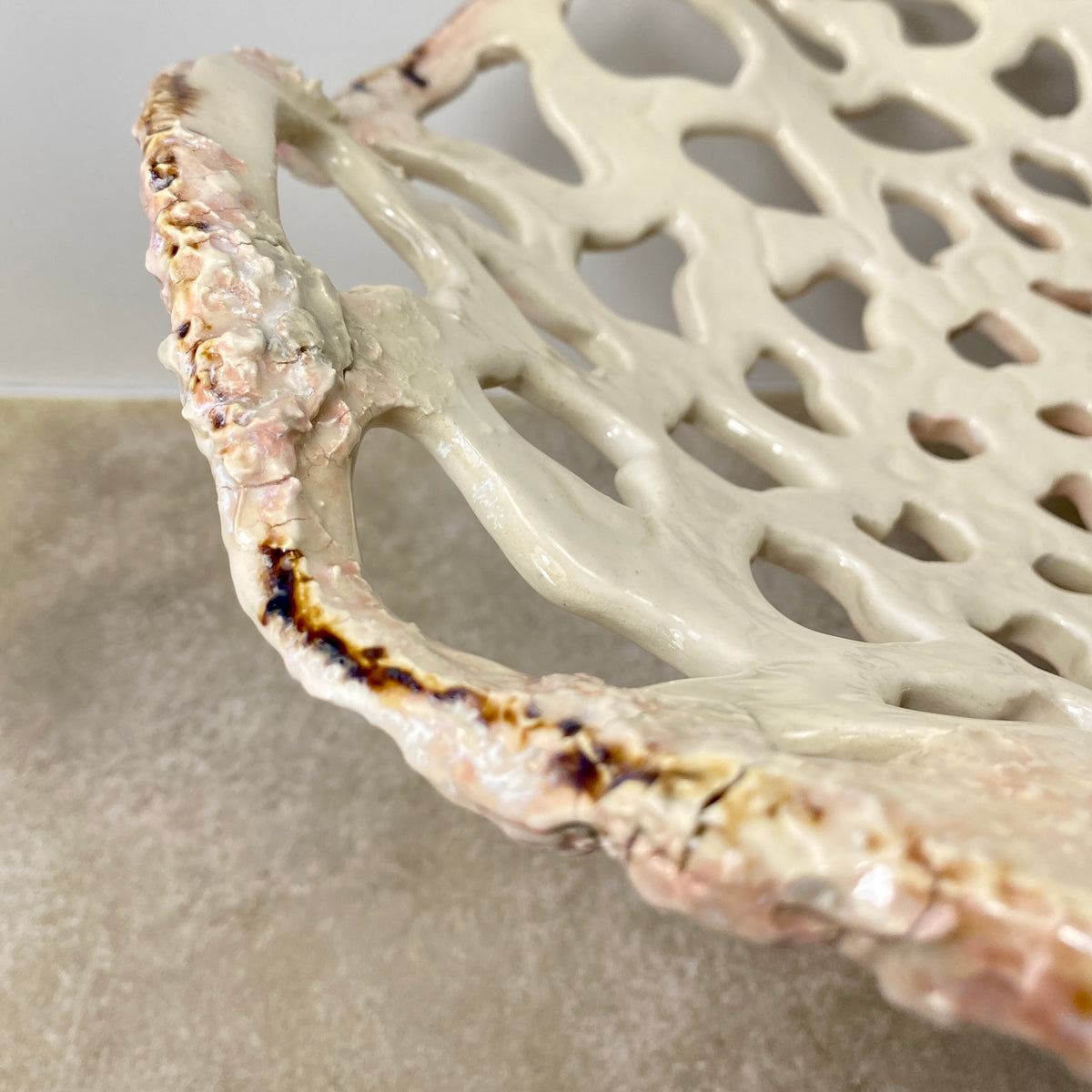 Openwork: Coastal — Sanddollar, close-up detail of rim showing warm blush and amber glaze breaks where kiln caught the edge