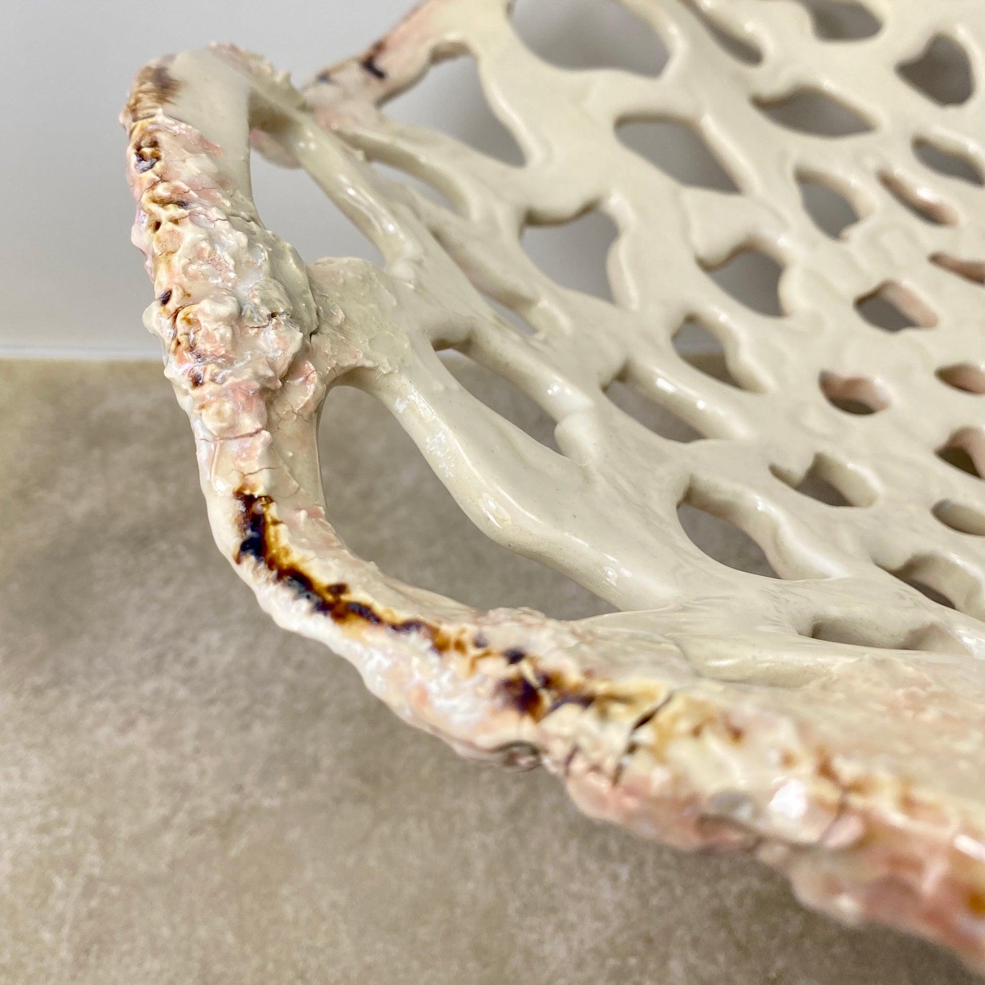 Openwork: Coastal — Sanddollar, close-up detail of rim showing warm blush and amber glaze breaks where kiln caught the edge