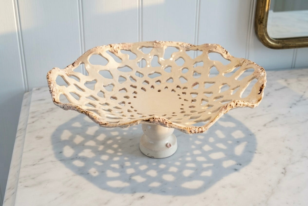 Openwork: Coastal — Sanddollar on marble surface, three-quarter view showing pedestal base and cream-to-blush glaze