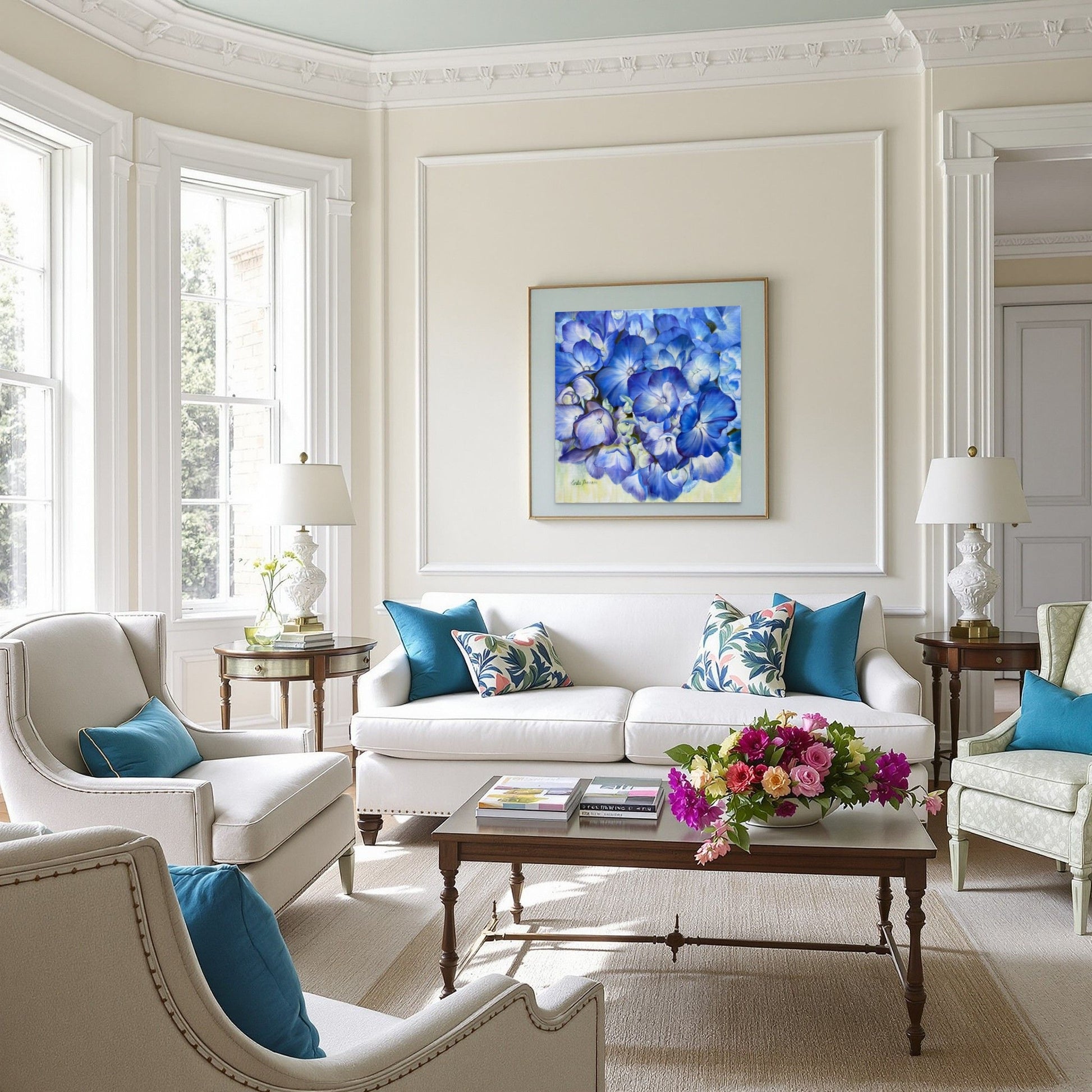 Living room with Echoes of Blue original oil painting over white sofa, armchairs, and a coffee table with flowers.
