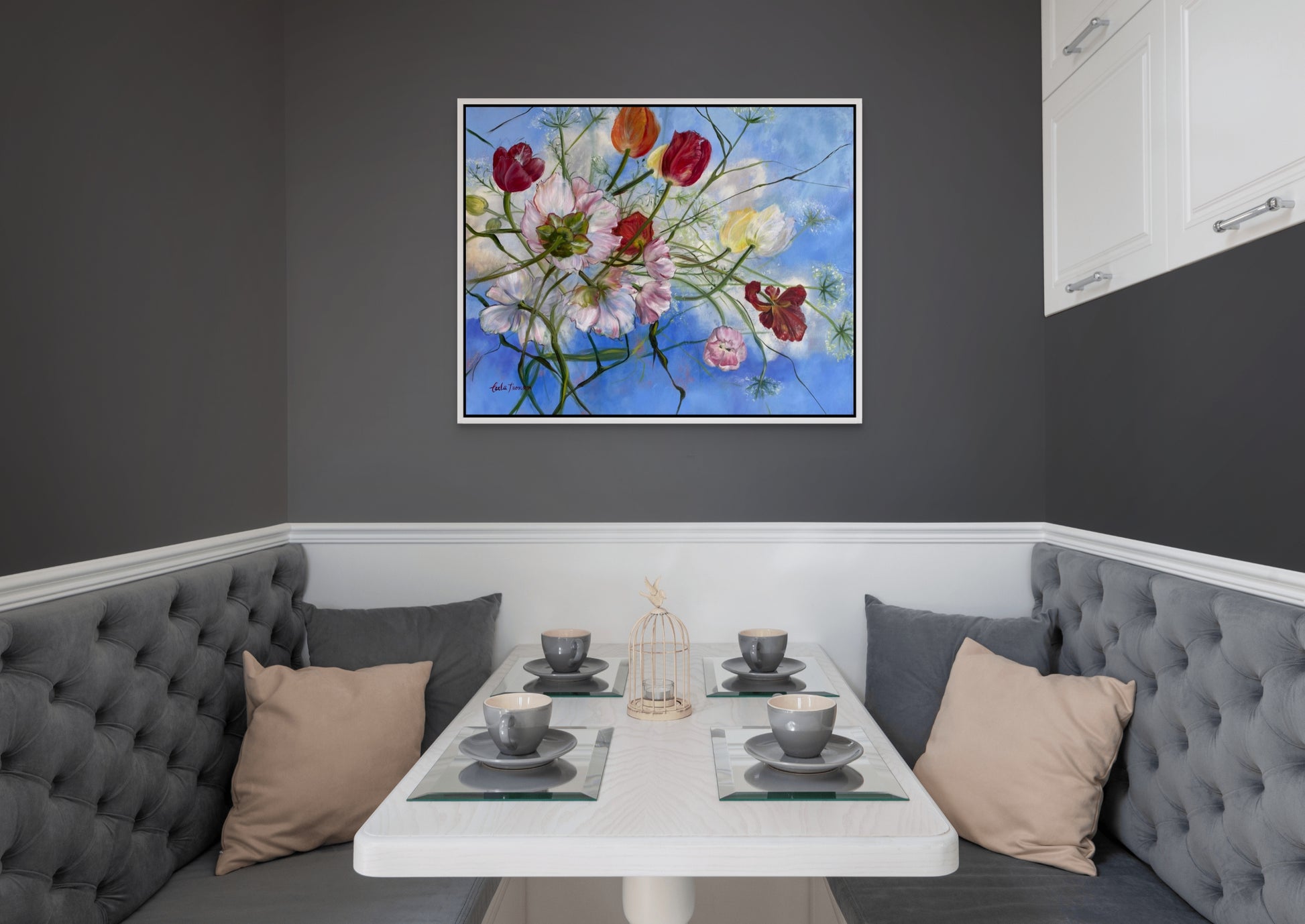 Wishful Thinking a colorful original floral oil painting on a gray wall over a Dining area with gray booth seating, and a small table set for four.