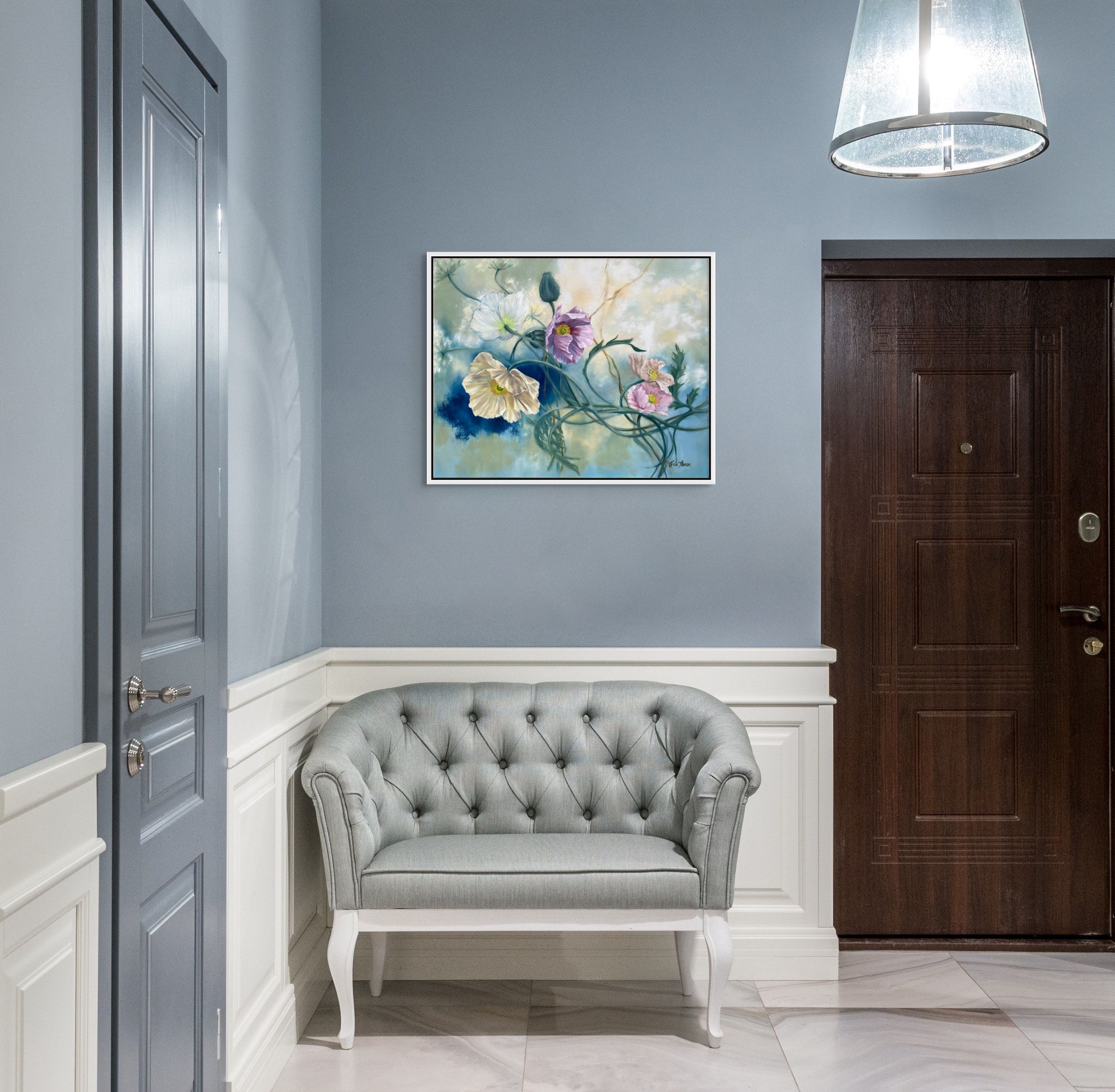 Foyer with gray tufted sofa, original floral oil painting Tangled Reverie on wall, and wooden door.